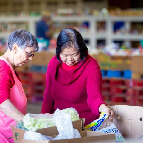 Two volunteers boxing up food at the MCFB warehousefor distribution