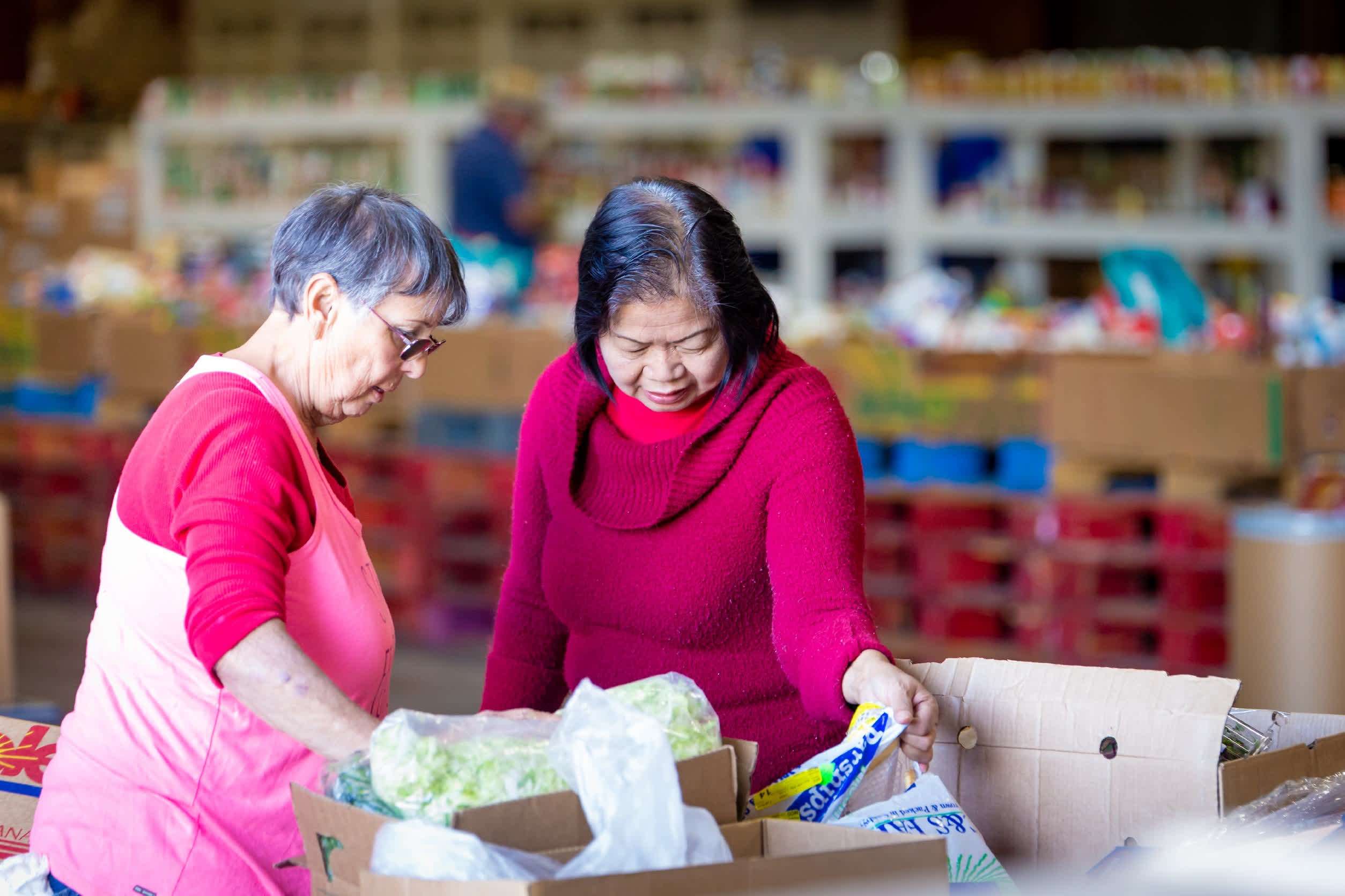 Two volunteers boxing up food at the MCFB warehousefor distribution