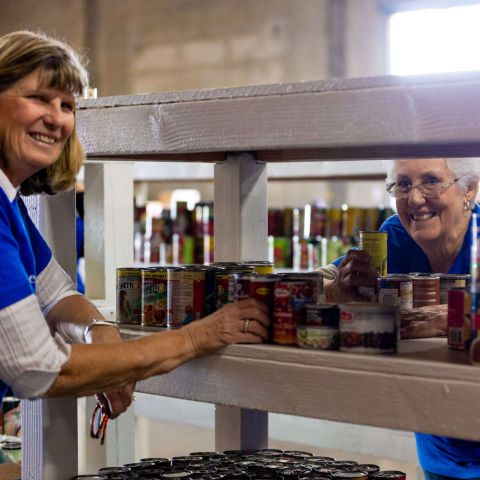 Two women volunteers organizing canned goods at the MCFB warehouse