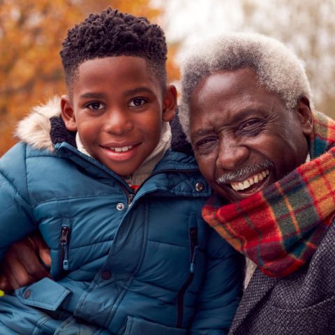 Portrait Of Smiling Grandfather And Grandson On Walk Through Autumn Countryside Together