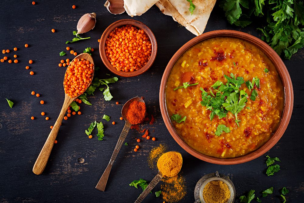 Indian dal. Food. Traditional Indian soup lentils. Indian Dhal spicy curry in bowl, spices, herbs, rustic black wooden background. Top view. Authentic Indian dish. Overhead. Flat lay